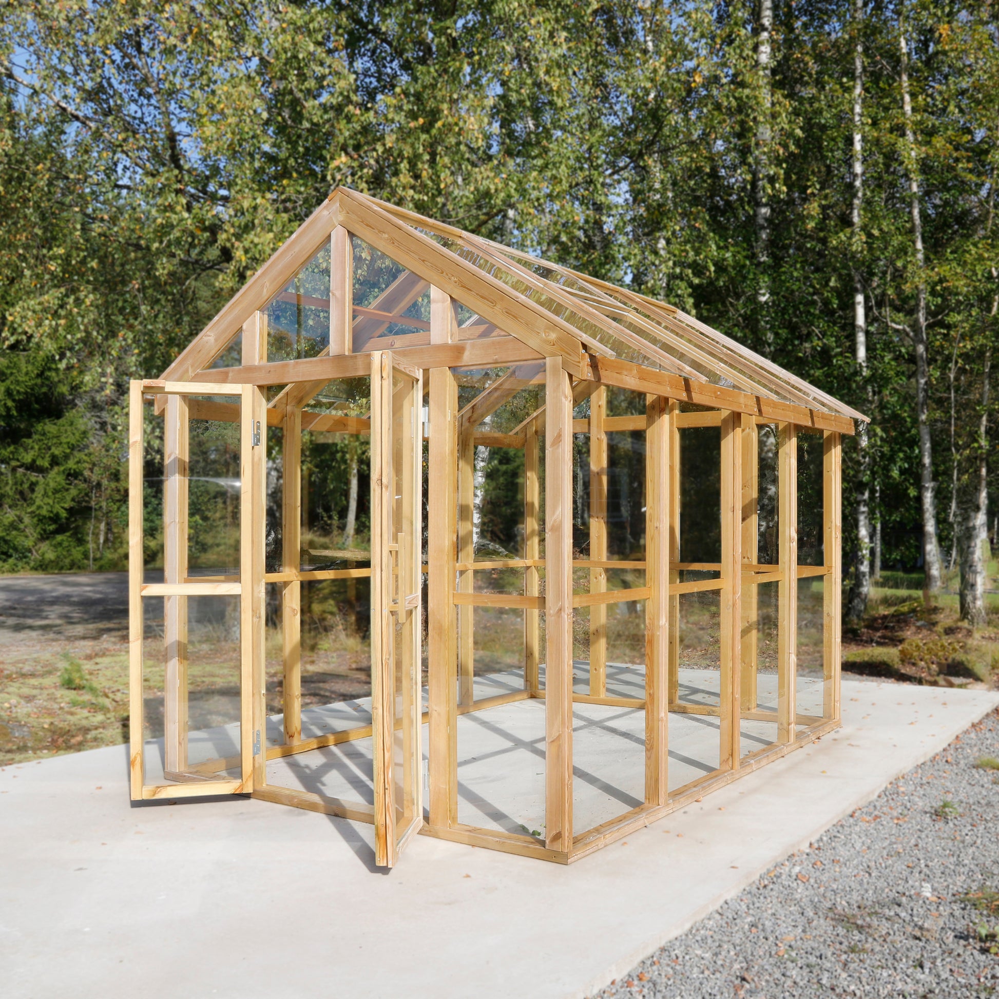 Växthus i trä med sadeltak och stora glaspartier – stilren och ljus design för odling i trädgården.